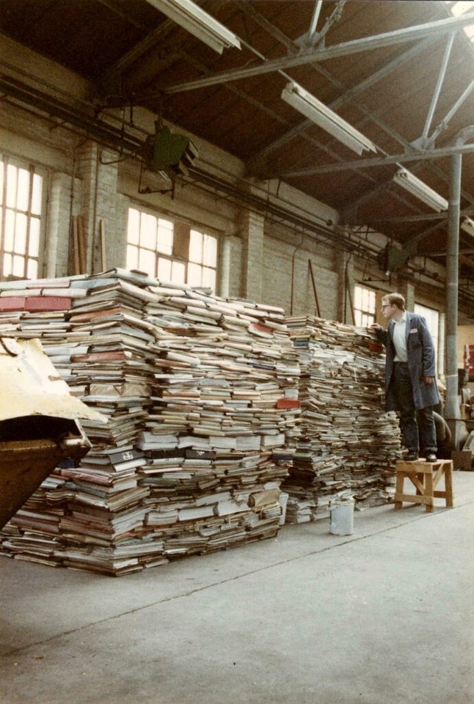 Records management rescue of shipyard records. Piles of records wwhich are being accessed by a person on a step