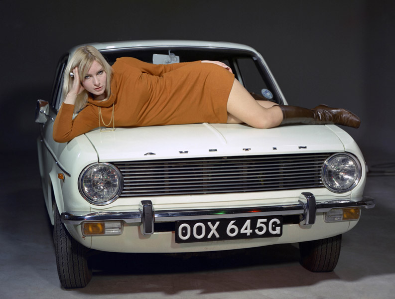 Colour image of an Austin Maxi car with a woman reclining on the bonnet.